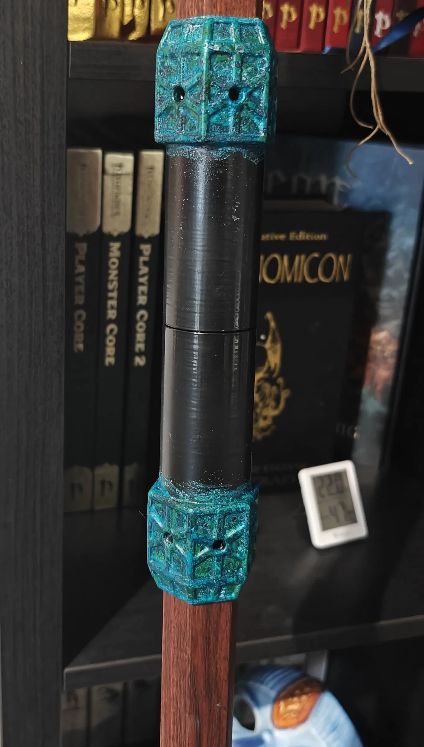 Close-up of a grip with corroded copper end pieces on a red wooden shaft