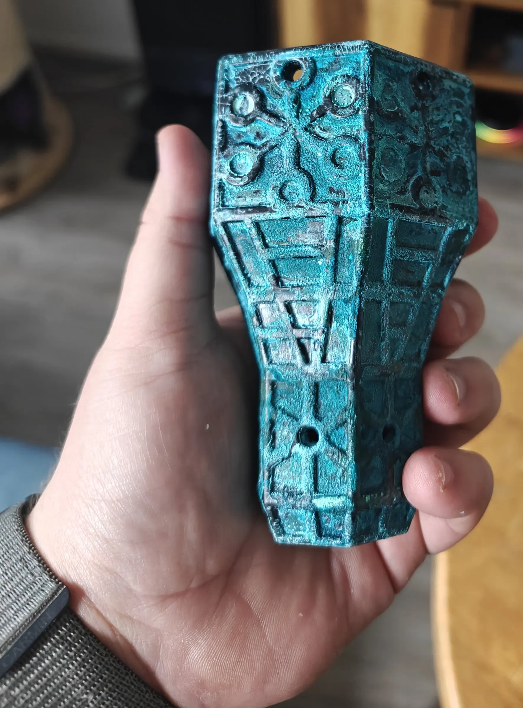 Corroded copper topper held in a hand, showing its size