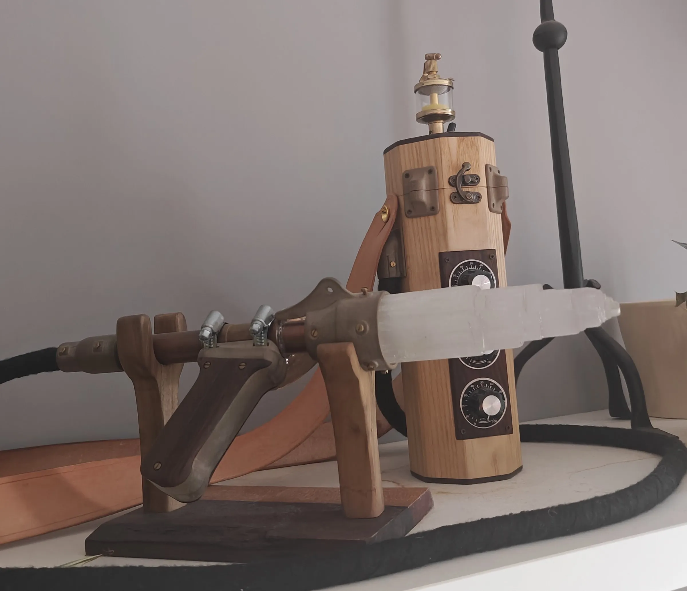 Side view of the wand on its stand, connected by a hose to the canister