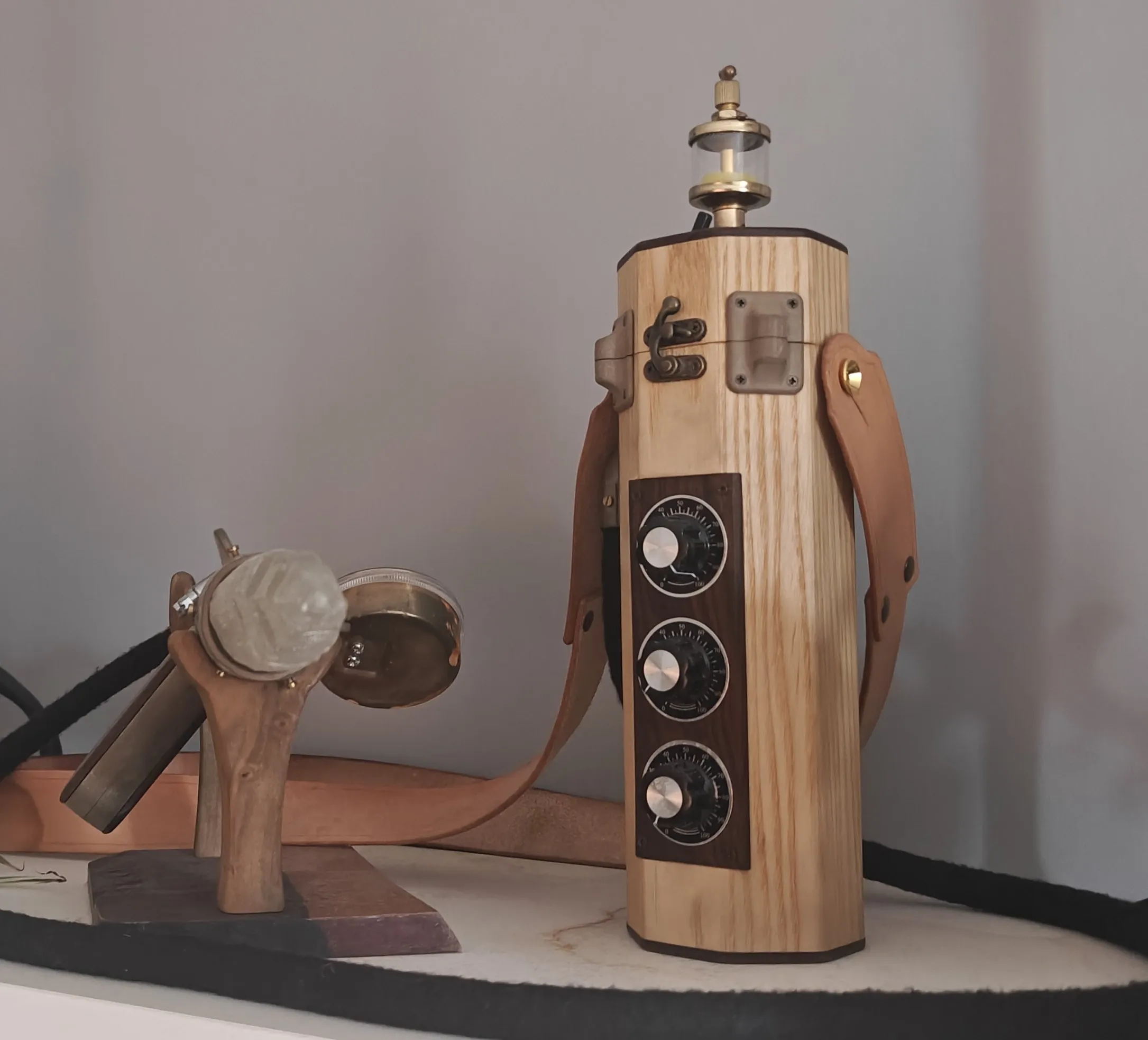 Front of the wooden canister with three dial knobs and a brass top