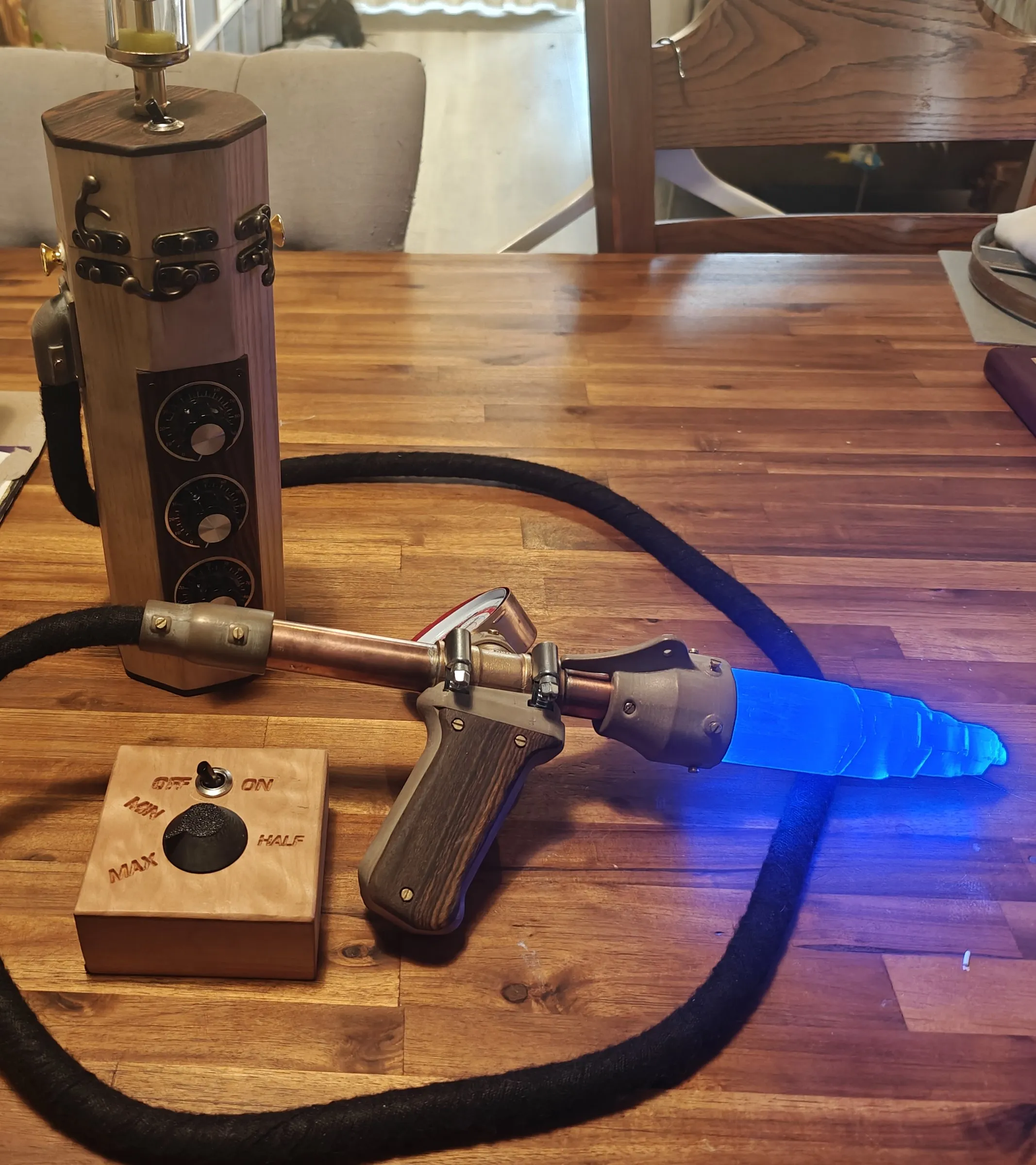 The full kit lit blue, with the wand, hose, wooden canister with three knobs, and a small wooden remote
